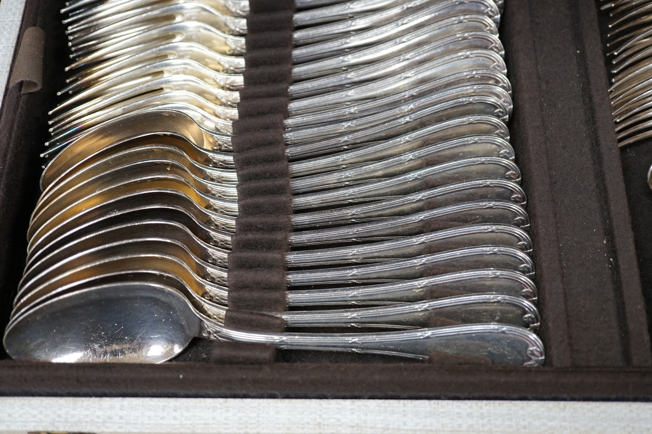 A cased canteen of French Christofle silver plated bow pattern cutlery, a twelve piece setting contained within two layers, case 49.5cm wide, 31cm deep, 13.5cm high